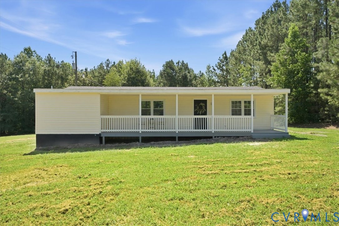 Single-story residence featuring light-colored siding, a covered front porch with white railings, and multiple windows