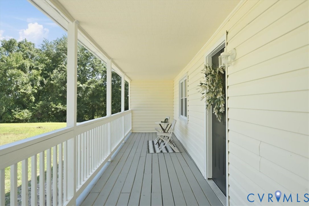 Covered porch with painted wood-finish flooring, white siding, and white railing
