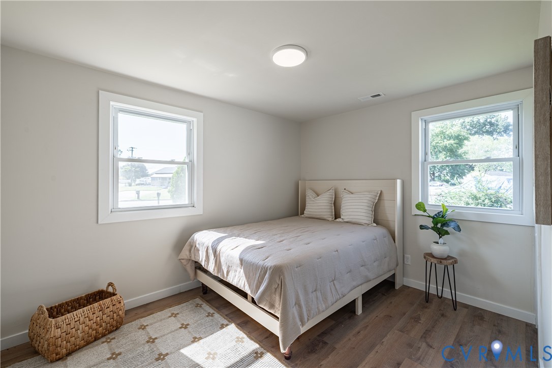 Recessed ceiling lighting, two windows with white trim, light tone wall paint, wood-finish flooring, and white baseboards