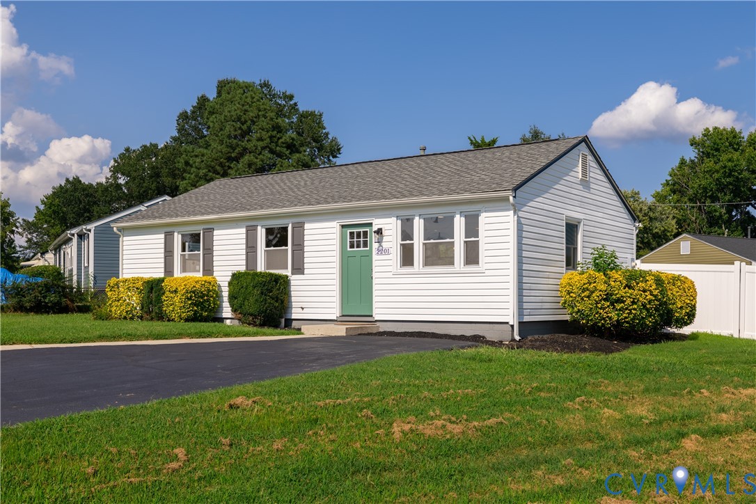 White siding exterior with a charcoal shingle roof, a green entry door, and dark gray window shutters