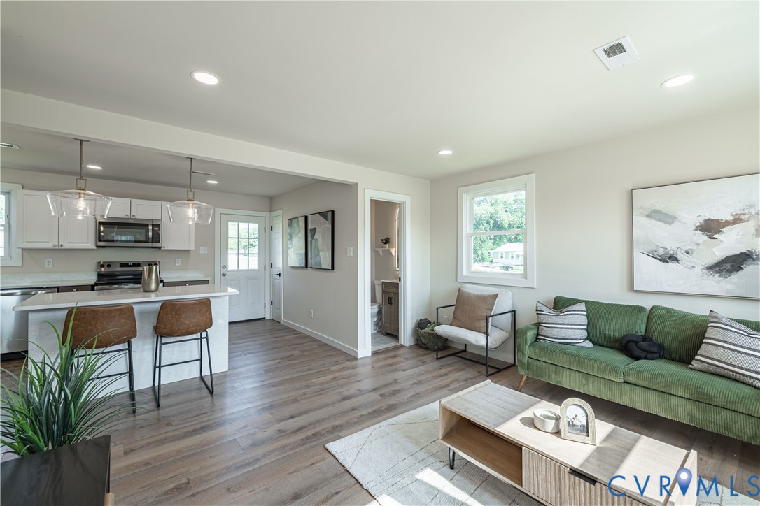 Open-concept living area featuring wood-finish flooring, recessed lighting, and a kitchen island with pendant lighting Open-concept living area featuring wood-finish flooring, recessed lighting, and a kitchen island with pendant lighting
