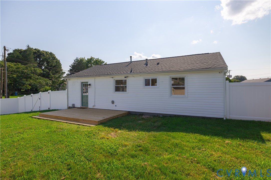 Private rear yard with wood deck, white vinyl fencing, and white siding exterior