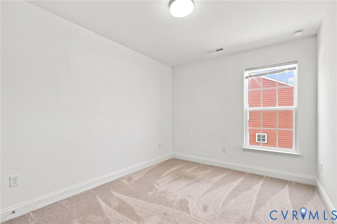 Neutral wall color, light-toned carpet, single window with blinds, ceiling-mounted light fixture, white trim