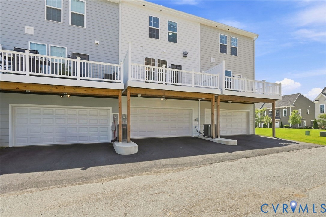 Multi-level townhouse exterior featuring multiple garage bays, individual decks, and gray horizontal siding