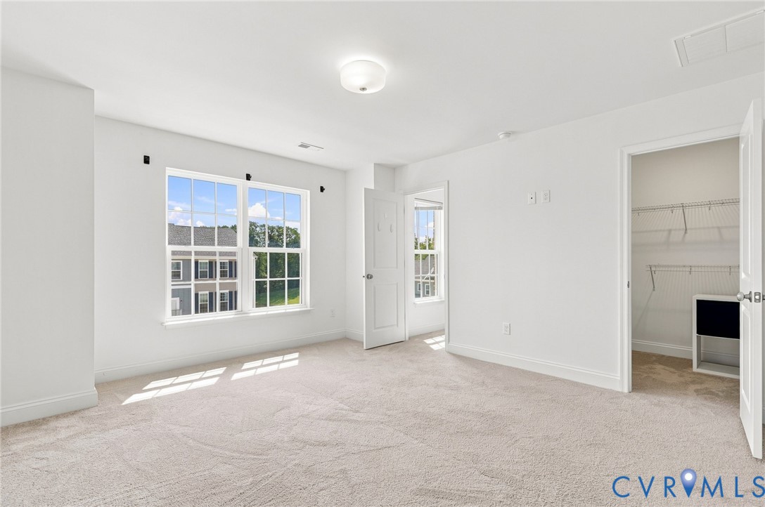 Bright interior with neutral carpeting, large double window, and a built-in closet system