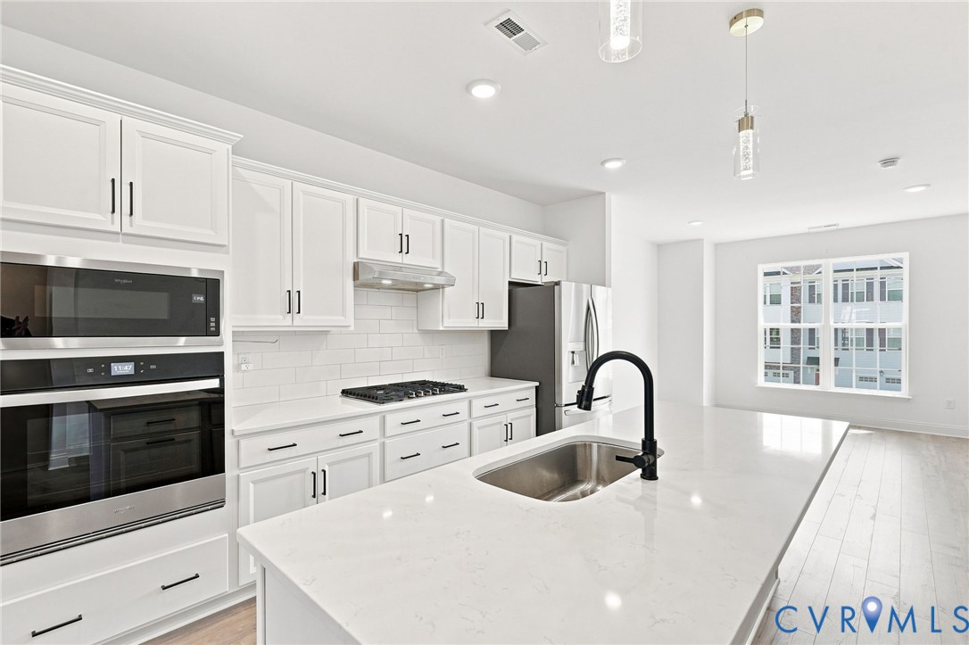 White cabinetry with black hardware, stainless steel appliances, and a gas cooktop