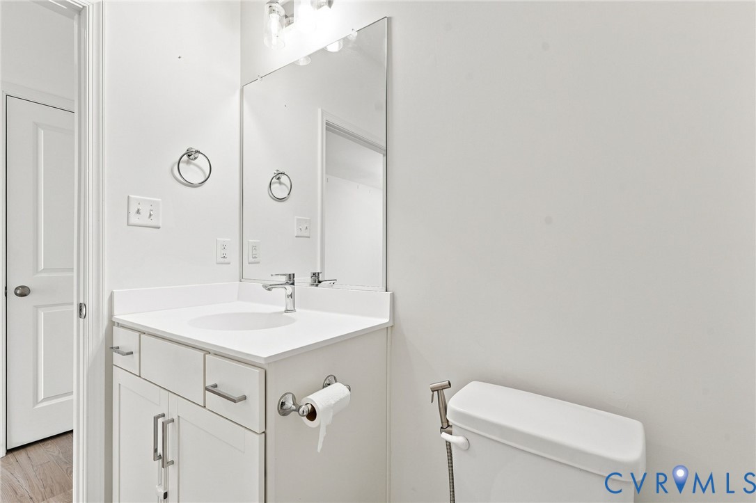 Vanity with an integrated sink, polished chrome faucet, built-in cabinetry, wall-mounted mirror, and overhead vanity lighting