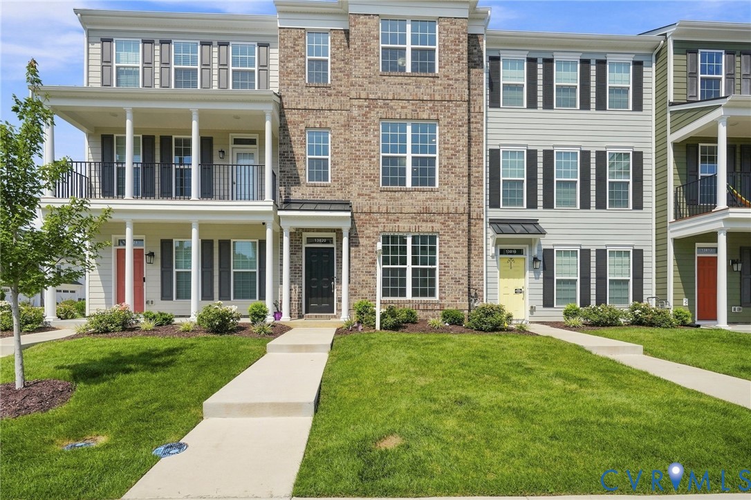 Brick and siding exterior with dark shutters, multiple balconies, and front entry sidewalk Brick and siding exterior with dark shutters, multiple balconies, and front entry sidewalk