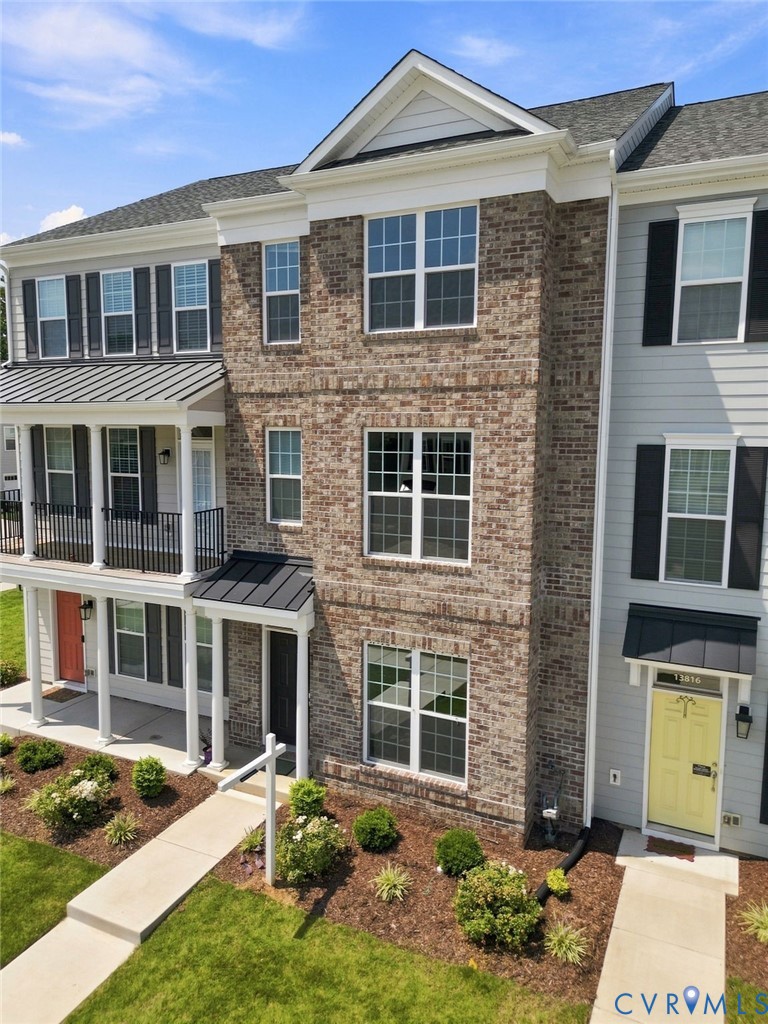 Brick exterior with multiple windows, covered entrance, and a balcony