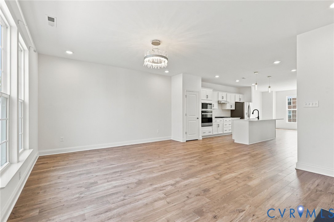 Open-concept living space featuring wood-finish flooring, recessed lighting, and a modern chandelier