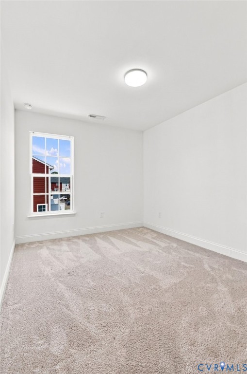 Neutral-toned carpeting, white walls, and a flush-mount ceiling light fixture