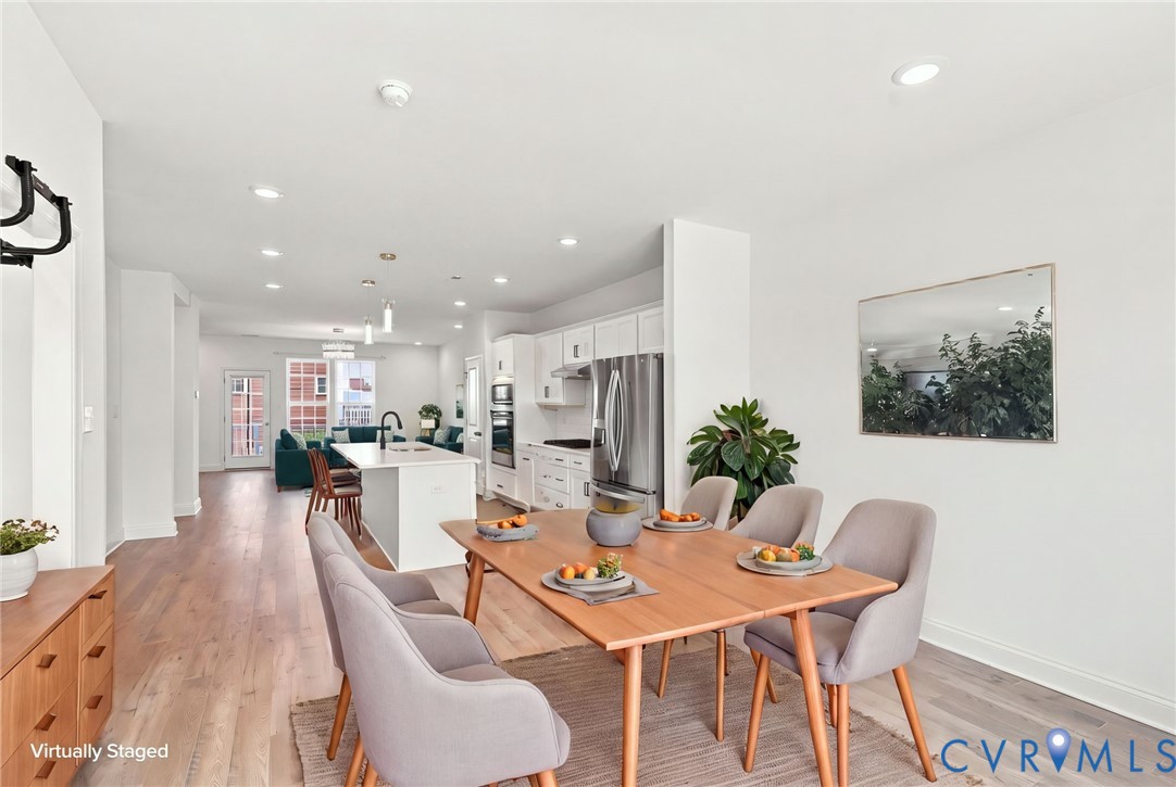 Open-concept living space with light wood-finish flooring, recessed lighting, and white walls