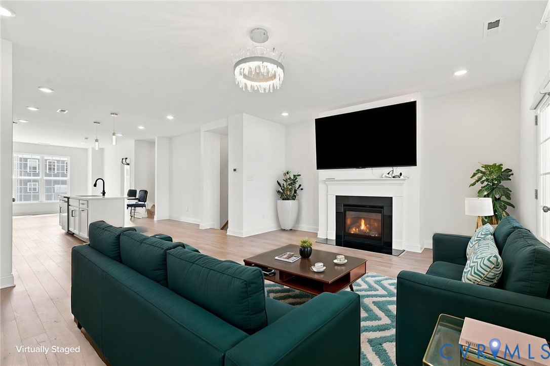 Open-concept living area with wood-finish flooring, recessed lighting, and a modern chandelier