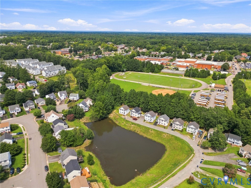 Neighborhood setting featuring a large pond, extensive green spaces, a sports field, and a track