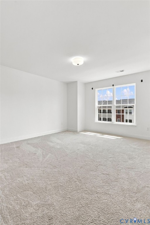 Spacious interior with neutral carpeting, white walls, and abundant natural light from a multi-pane window