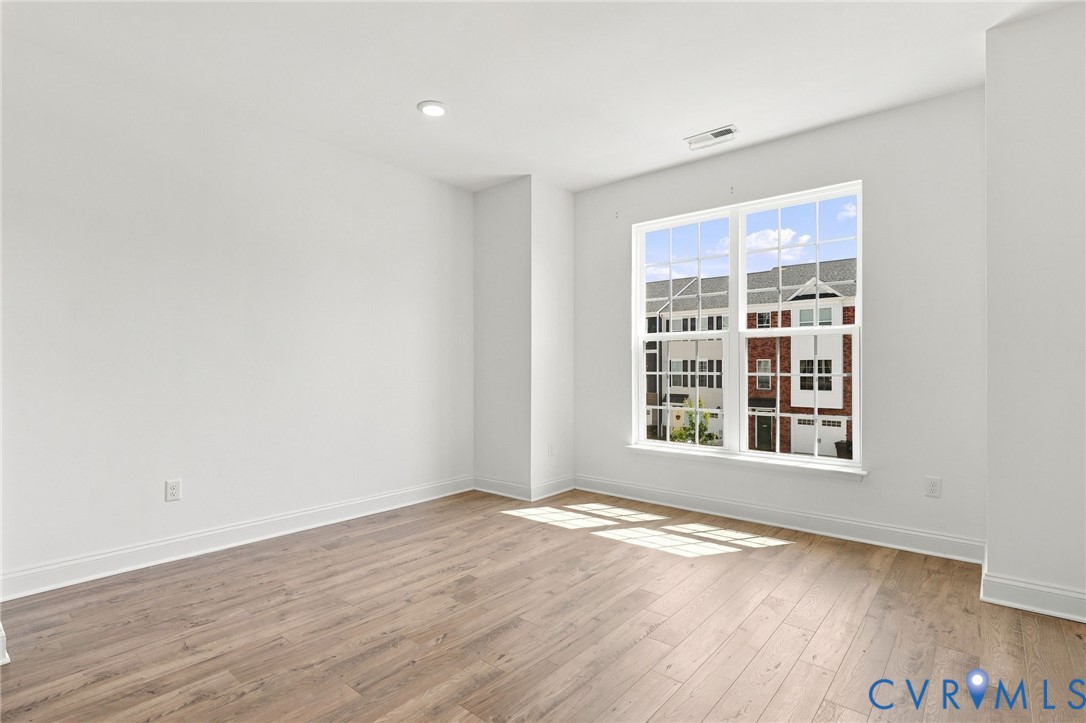 Wood-finish flooring, white walls, recessed ceiling lighting, and a large window with grid pattern