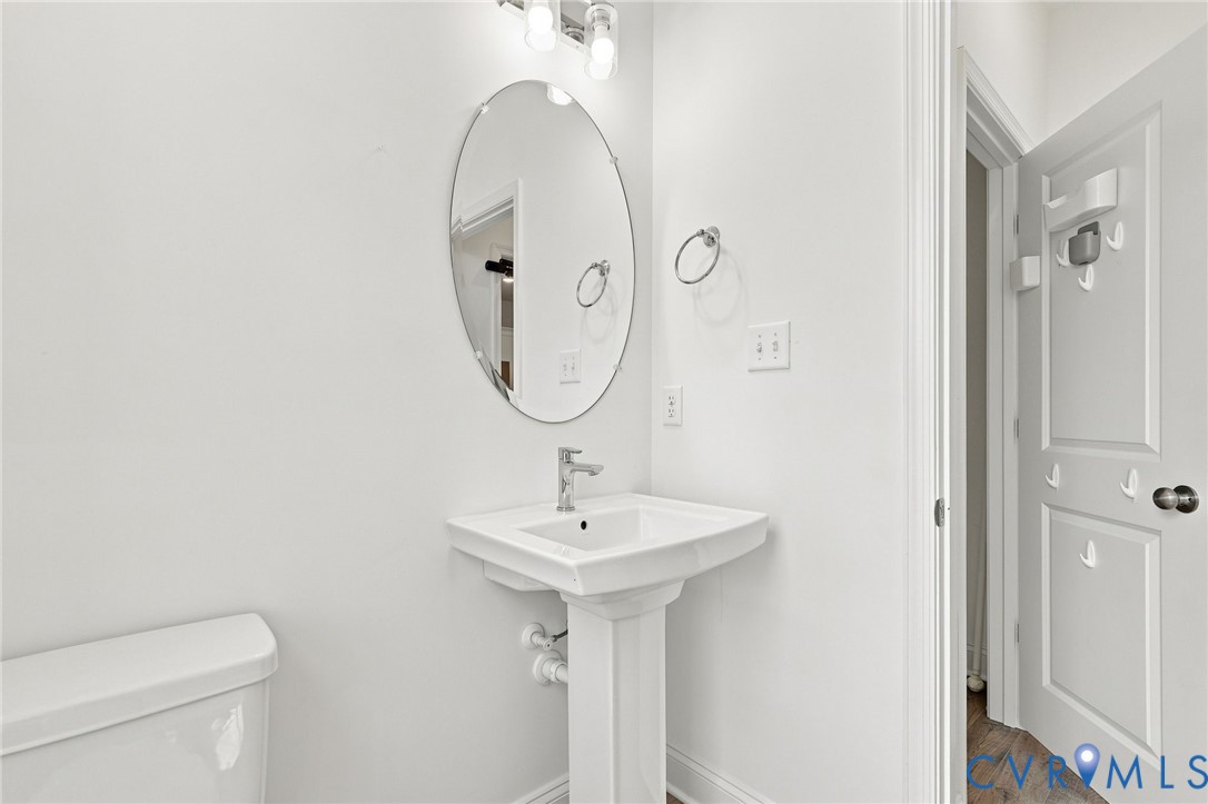 Pedestal sink with chrome faucet, oval mirror, and wall-mounted light fixture