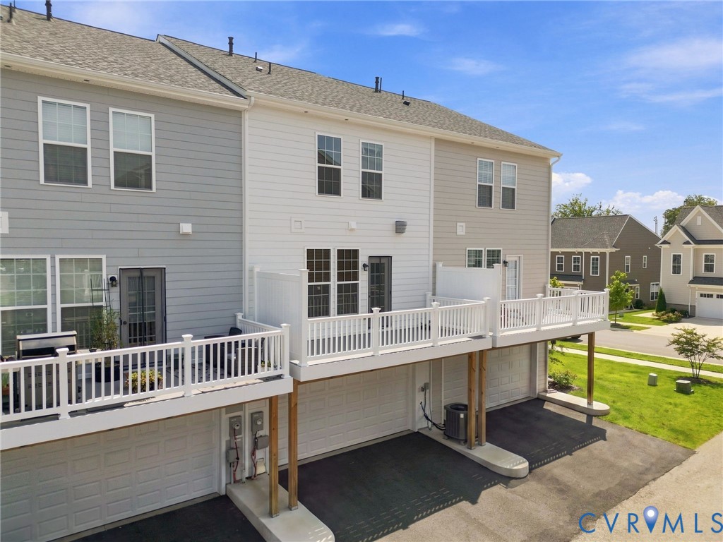 Multi-level property exterior featuring gray and white siding, dual-level decks with white railings, and integrated garage spaces