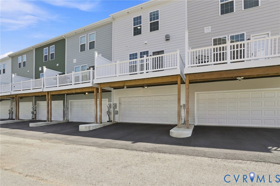 Townhome exterior with light gray siding, private balconies, individual garages, and paved driveways
