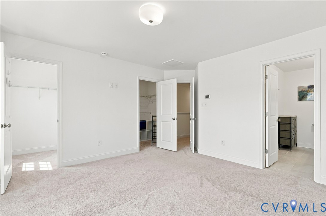 Expansive carpeted room featuring white walls, white doors, and a flush mount ceiling light