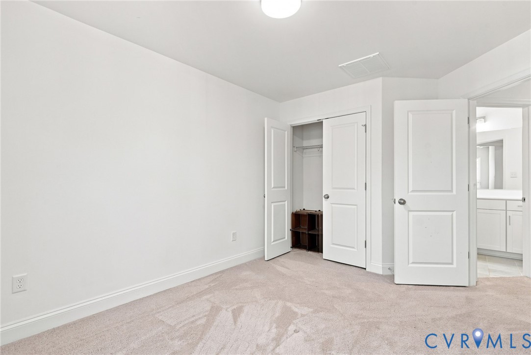Neutral carpeting, white painted walls, white trim, white interior doors, and a closet with bifold doors