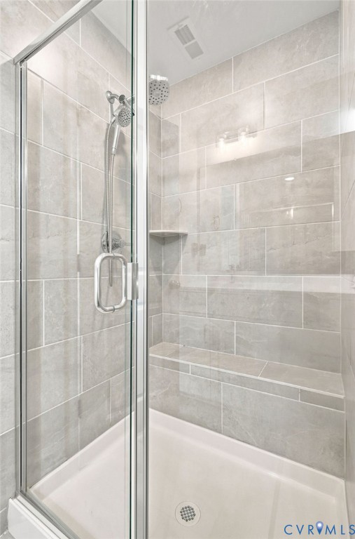 Glass-enclosed shower with tiled walls, integrated shelving, and a built-in bench