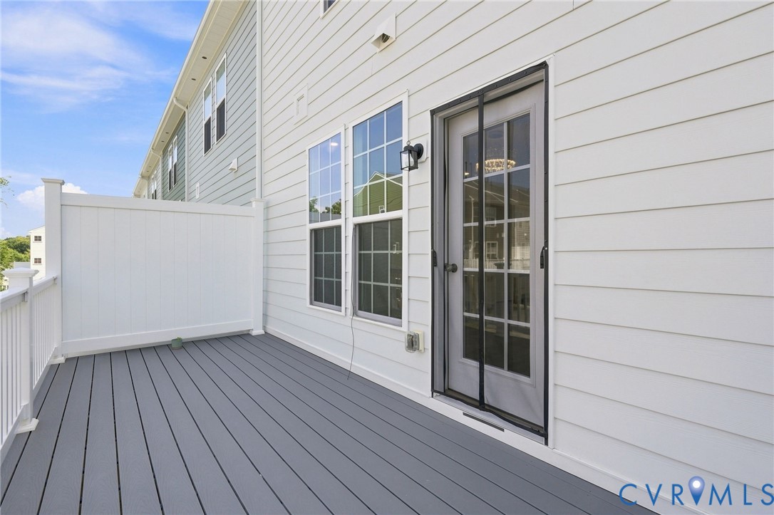 Exterior deck with gray composite decking, white privacy fencing, and white vinyl siding
