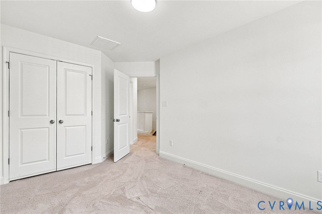 White walls, light-toned carpet, and a ceiling-mounted light fixture