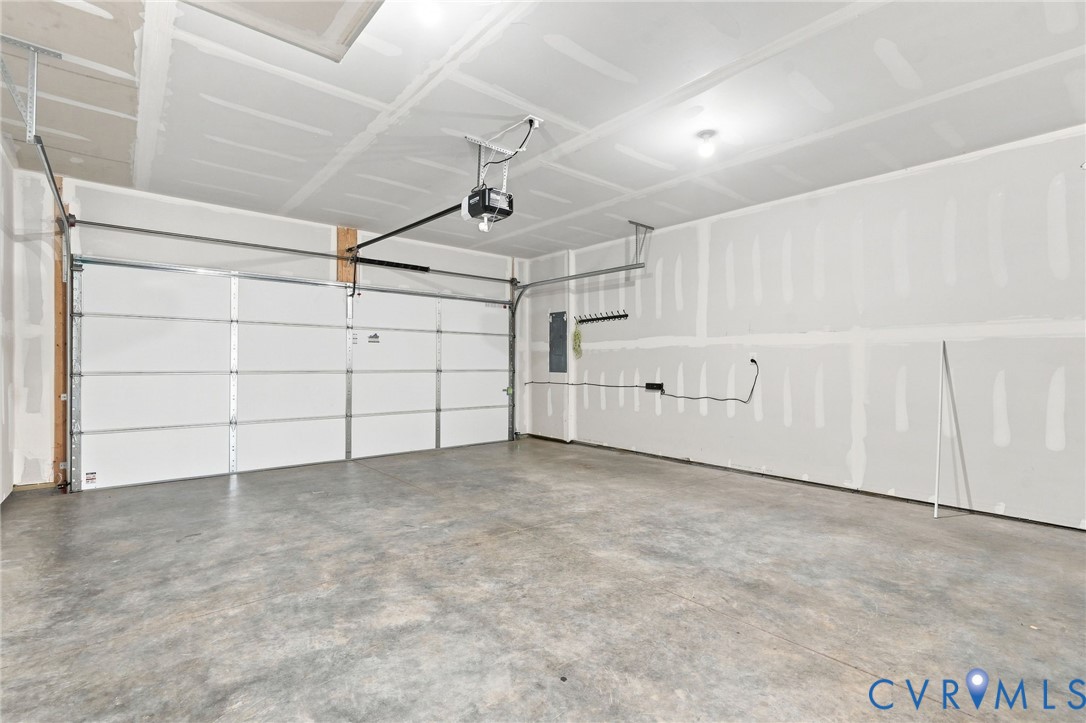 Concrete flooring, white overhead garage door, built-in garage door opener, overhead lighting Concrete flooring, white overhead garage door, built-in garage door opener, overhead lighting