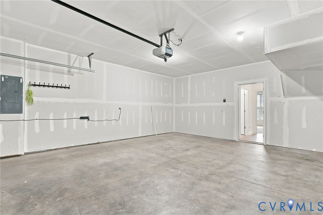Spacious garage with unfinished walls, concrete flooring, and an overhead garage door opener Spacious garage with unfinished walls, concrete flooring, and an overhead garage door opener