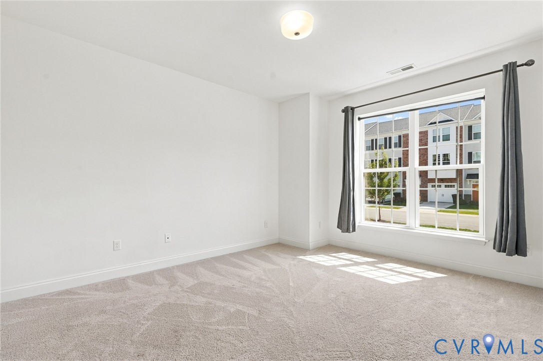 Wall-to-wall carpeting, white painted walls, and a multi-pane window with a light fixture