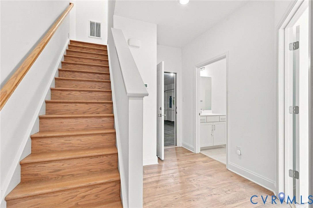 Wood-finish flooring, staircase with wood-finish treads and handrail, white painted walls, and white cabinetry in the adjacent room Wood-finish flooring, staircase with wood-finish treads and handrail, white painted walls, and white cabinetry in the adjacent room