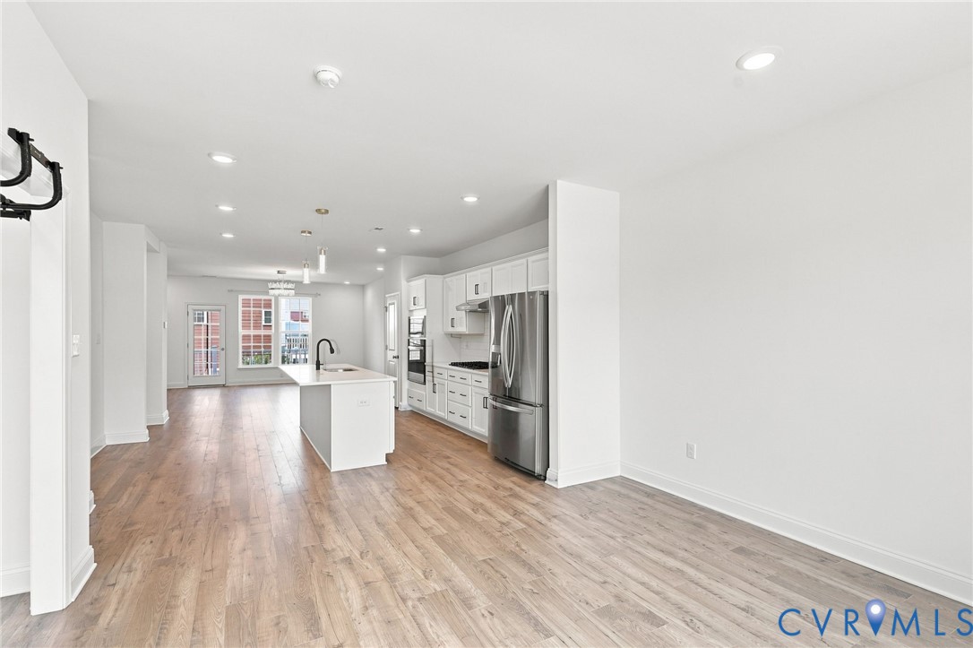 Bright open-concept interior featuring light wood-finish flooring, recessed lighting, and a kitchen island with pendant lighting