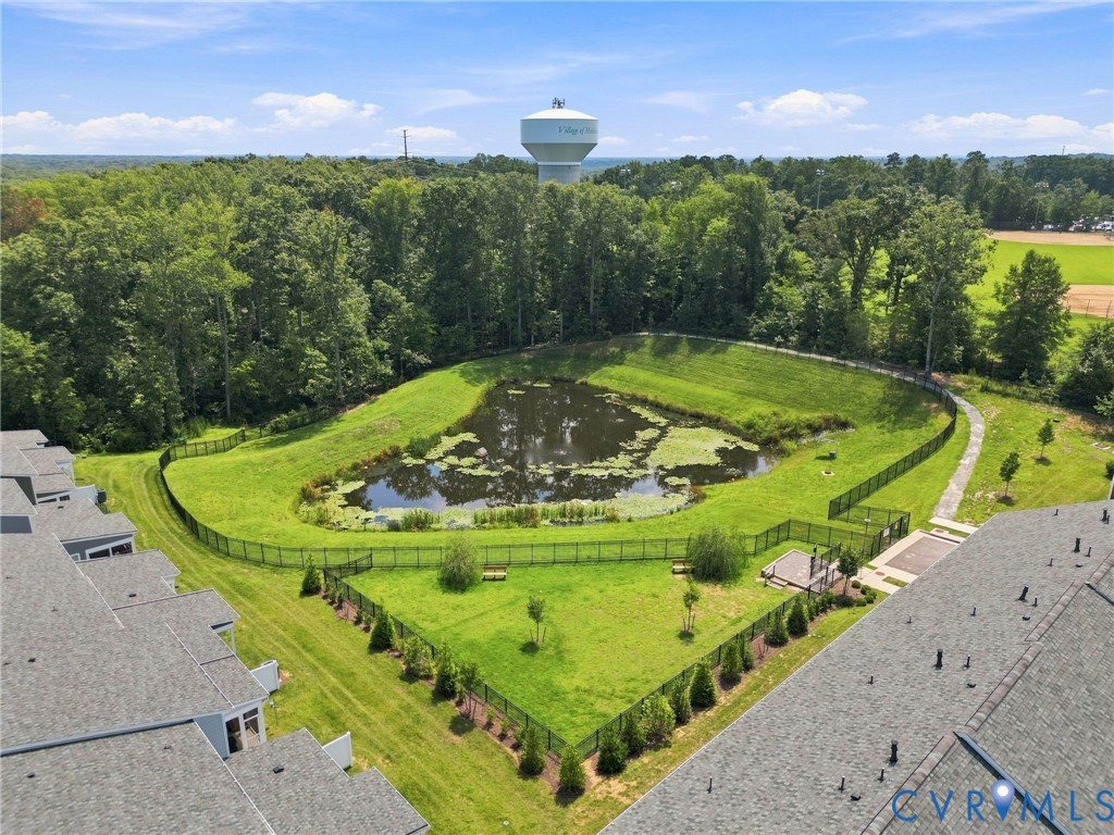 Landscaped grounds featuring a retention pond, surrounding green space, and a fenced pet amenity area