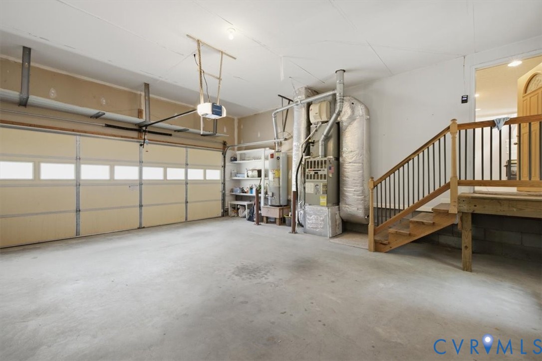 Spacious garage featuring a three-panel sectional door with frosted glass panels, polished concrete flooring, and integrated HVAC and water heater systems