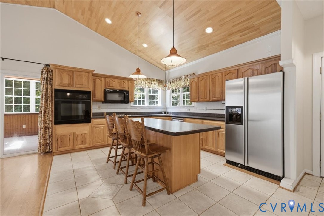 Spacious kitchen featuring custom wood cabinetry, stainless steel appliances, and a large center island with seating for multiple guests