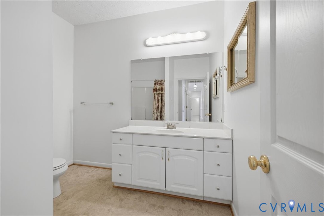 White vanity with a single sink, large wall-mounted mirror, and overhead strip lighting