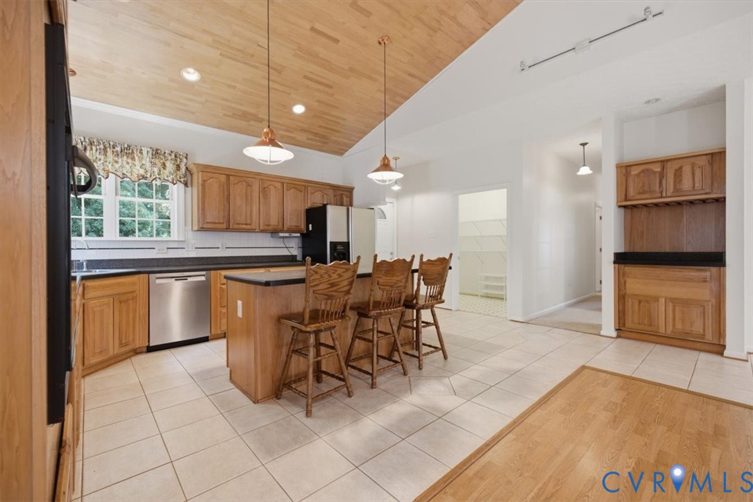 Spacious kitchen featuring wood cabinetry, stainless steel appliances, and a center island with seating
