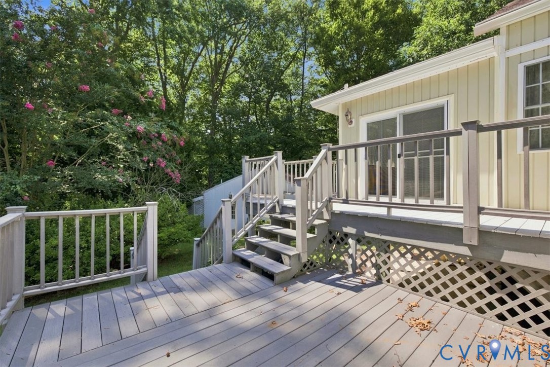 Expansive composite deck featuring multiple levels with white railings, hardwood-finish decking, and integrated lattice skirting