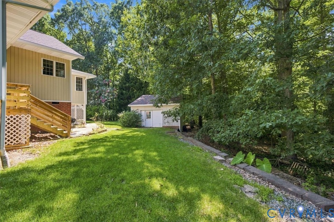 Spacious rear yard with expansive lawn, elevated wood deck, and detached outbuilding