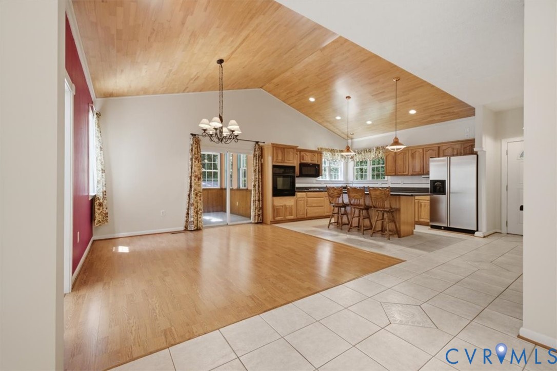 Vaulted wood-finish ceiling, wood-finish flooring, tile flooring, kitchen island with seating, and stainless steel appliances