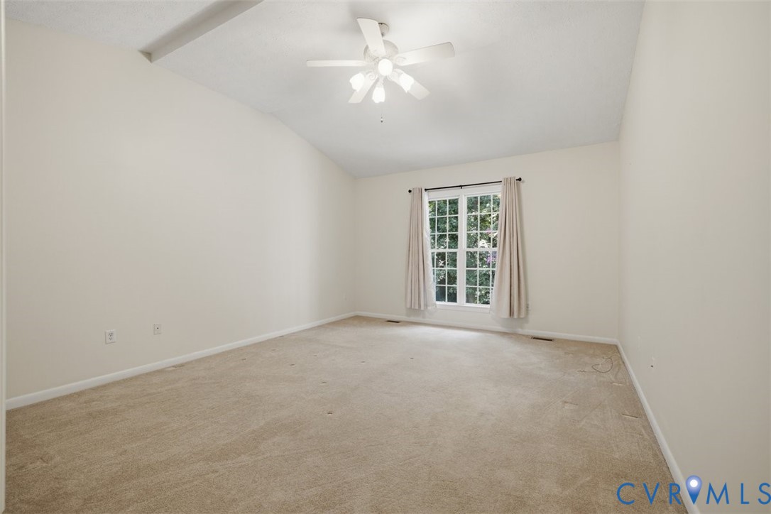 Bright bedroom featuring neutral carpet flooring, ceiling fan with integrated lighting, and glass door with curtain panels providing natural light from the exterior window frame