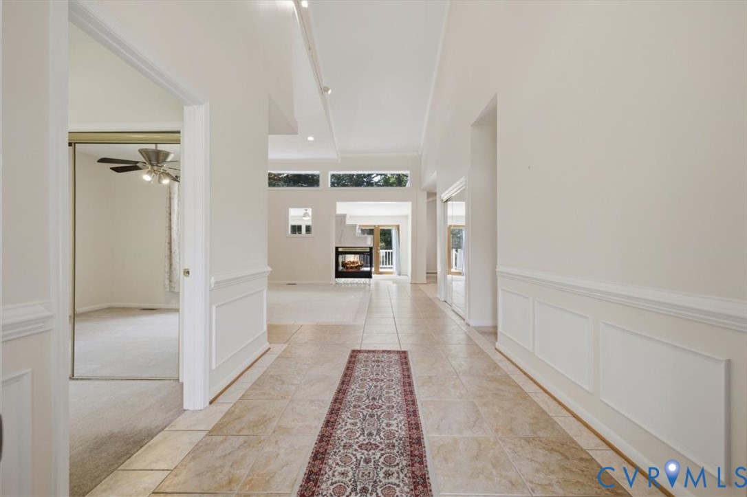 Tiled entryway featuring wainscoting and high ceilings