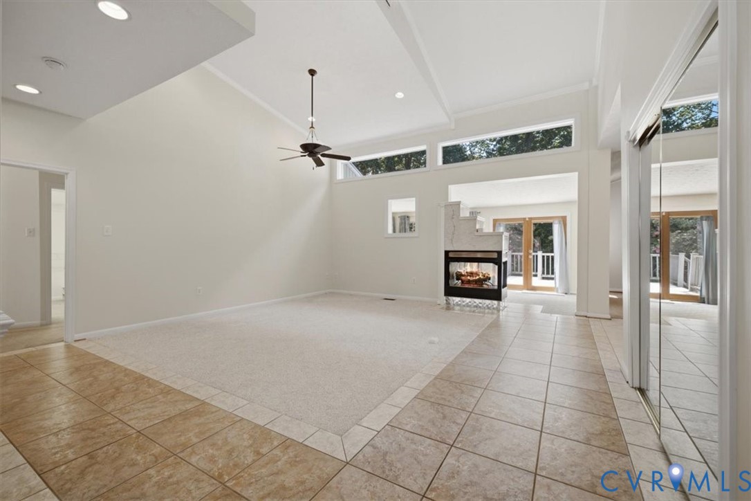 Spacious great room with soaring vaulted ceilings, clerestory windows flooding the space with natural light, and a ceiling fan for climate control