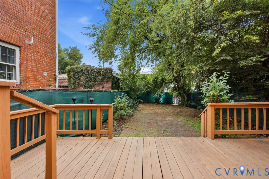 Spacious wood-finish deck with wood railings, leading to a landscaped yard with mature trees