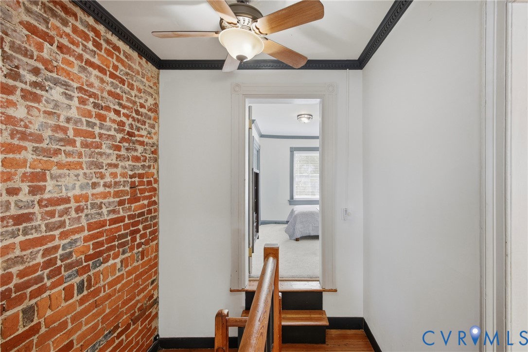 Exposed brick wall, hardwood flooring, view of 2nd bedroom