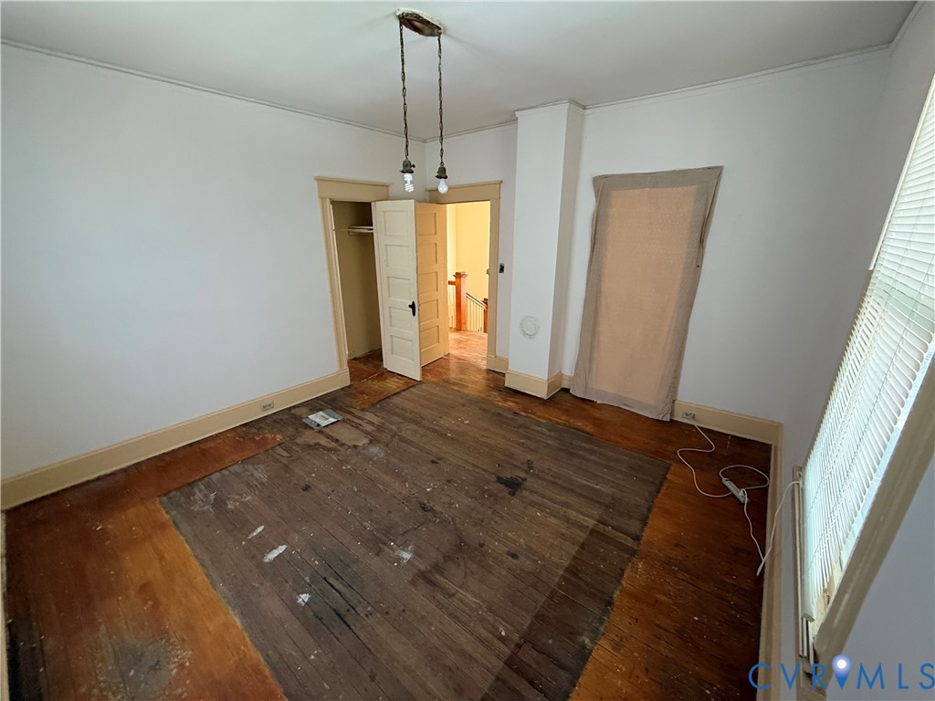Interior room with wood-finish flooring, white walls, and a recessed closet