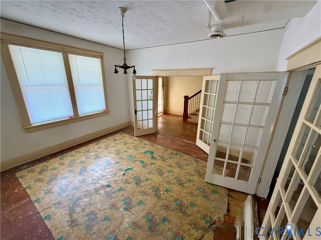 French doors with multiple lites, double windows with blinds, and a ceiling-mounted light fixture