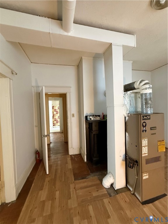 Wood-finish flooring with a central utility area, featuring a built-in dark wood cabinet and white walls