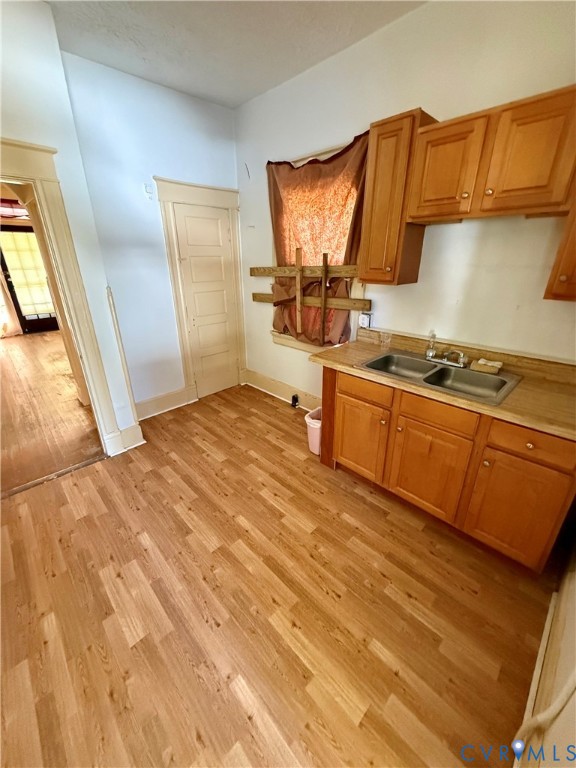Wood-finish flooring throughout, paired with a double-basin stainless steel sink, and wood cabinetry with coordinating upper and lower units Wood-finish flooring throughout, paired with a double-basin stainless steel sink, and wood cabinetry with coordinating upper and lower units
